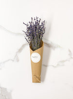 Load image into Gallery viewer, Lavender bunch wrapped in brown kraft paper with a SKIM Ceramics sticker. Staged on a white and gray background.
