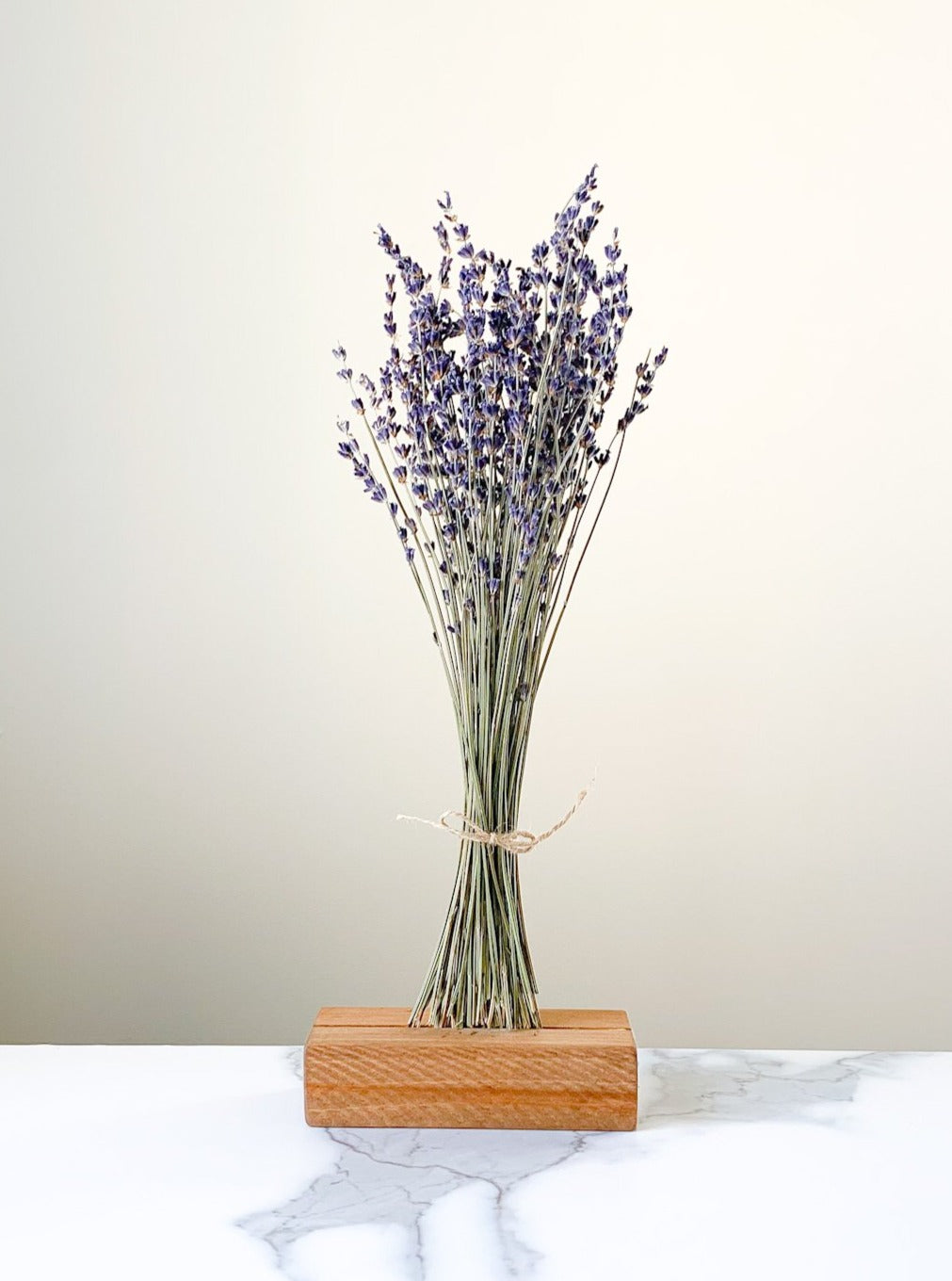 Lavender bunch staged in a wooden stand with a white and gray marble background.